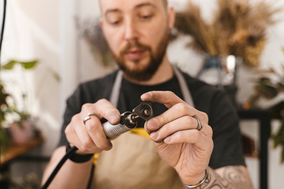 Focused artisan polishing a metal piece with rotary tool, highlighting precision and craftsmanship.